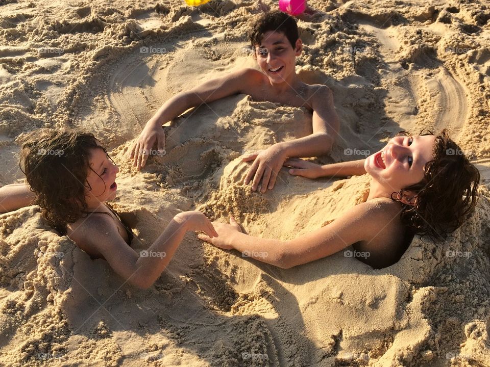 Little kids buried in the sand on beach