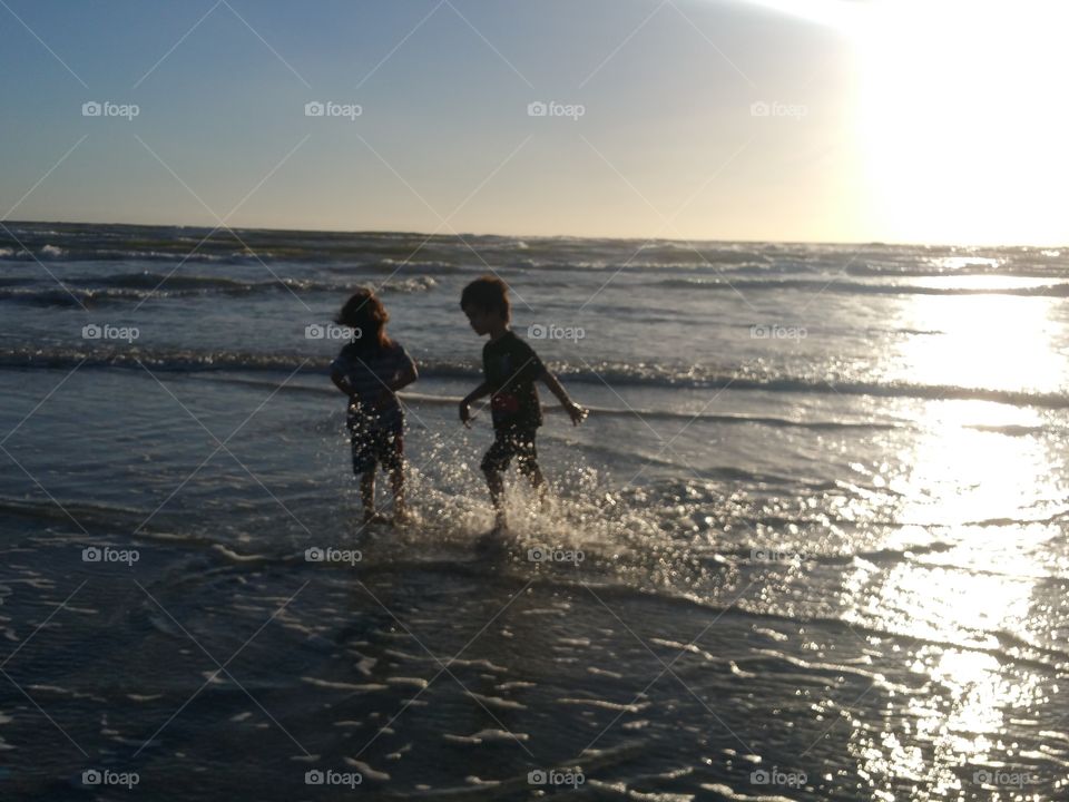 children playing in the water at sunrise