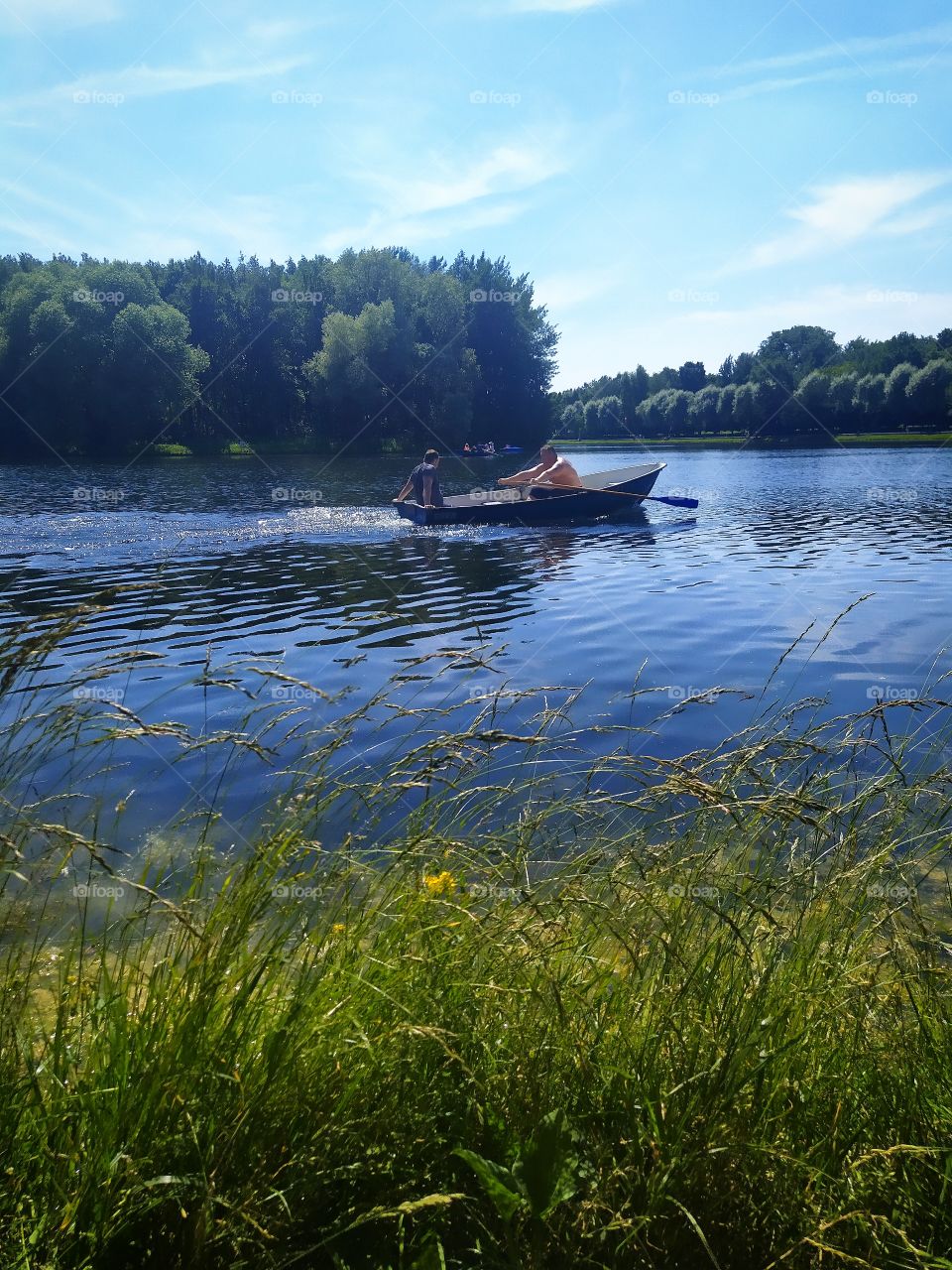 Summer rest.  A wooden boat with people is sailing along the river
