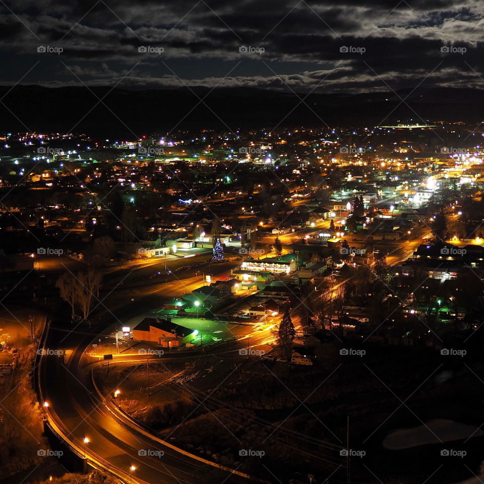 A small town in Central Oregon is brighly lit after dark by colorful Christmas lights and moonlight breaking through clouds. 