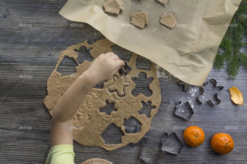 Christmas, gingerbread cookies on a wooden table sprinkled with flour, with tangerines and a green Christmas tree.