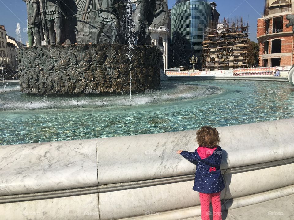 Baby girl waiting for the water from the fountain to go up...