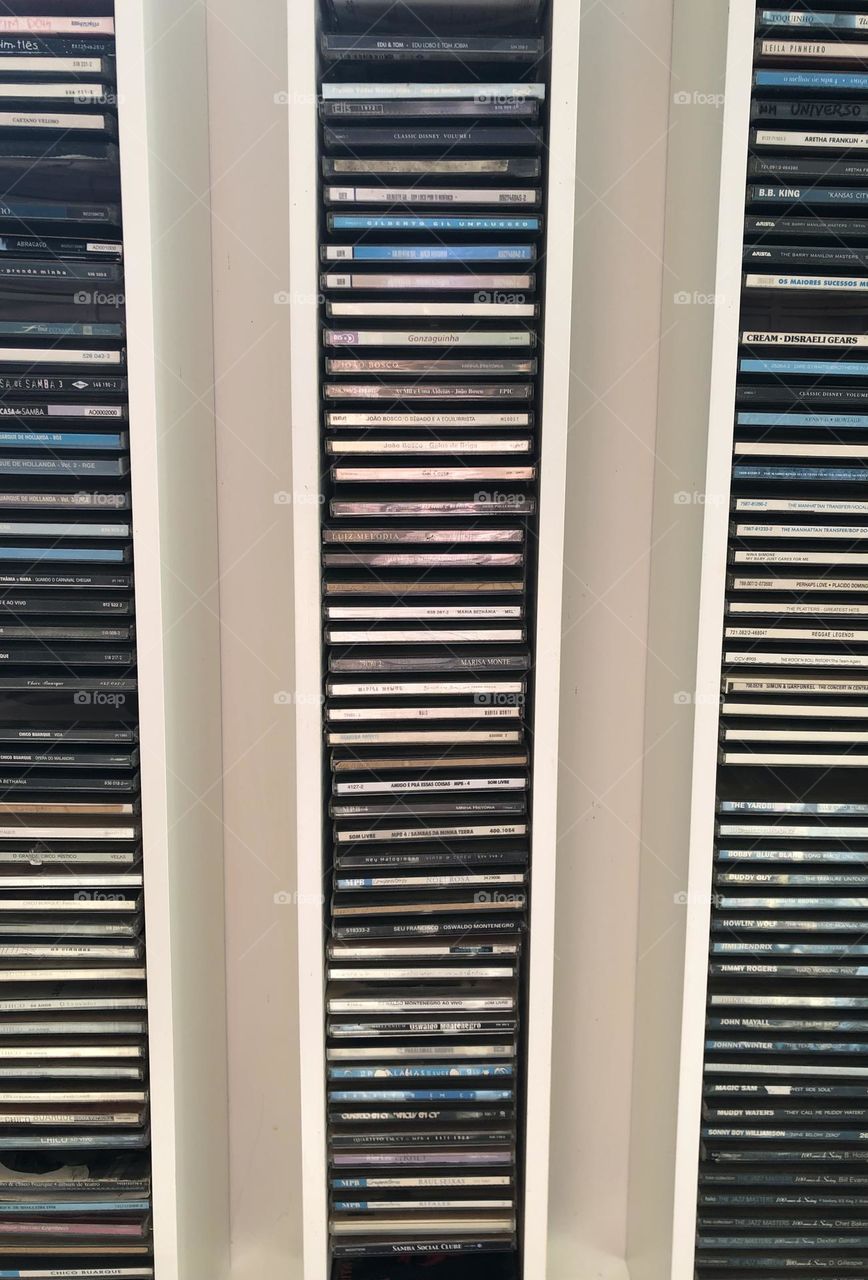 Three cd shelves with their vertical lines make rectangles on the wall while the cds are the horizontal rectangles. 