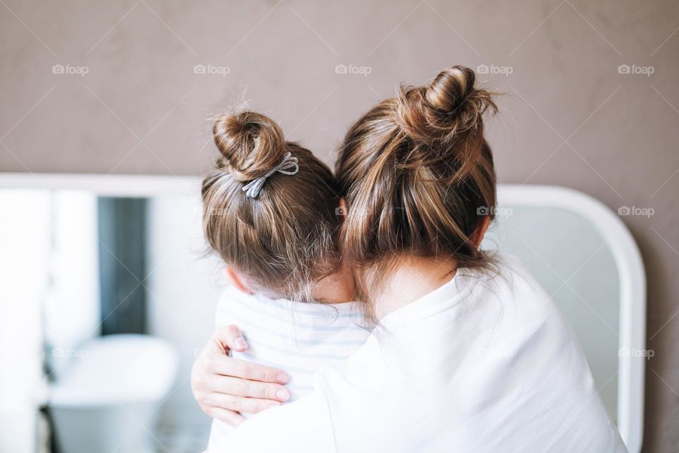 Young mother woman with long hair with little tween girl daughter in pajamas having fun in the morning at home, family spending time together in bathroom