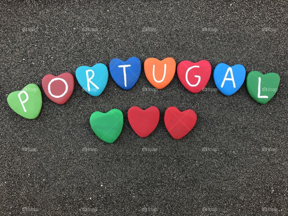 Portugal country name with colored heart stones over black volcanic sand