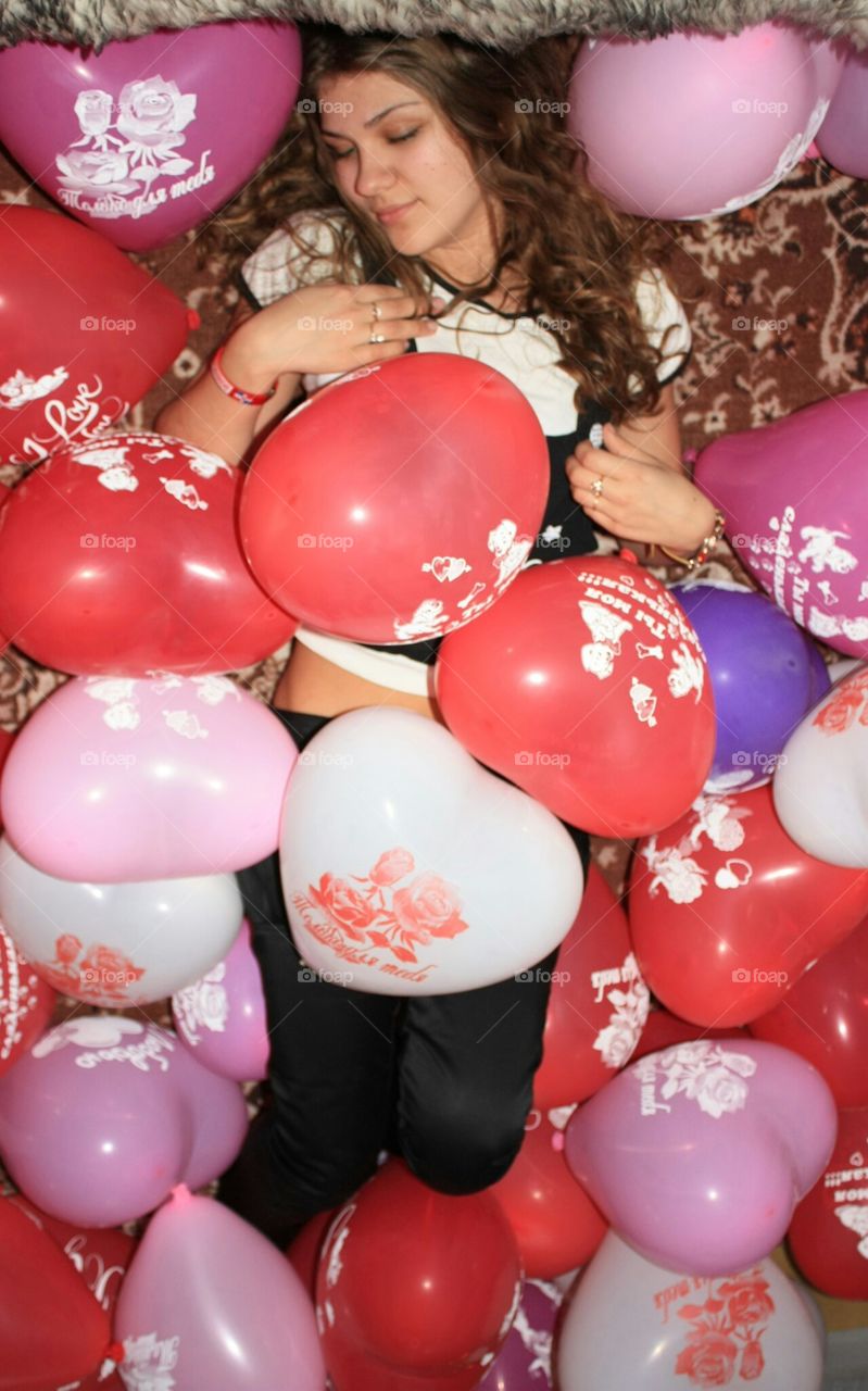 Girl with close eyes is lying in heart balloons. Girl with close eyes is lying in heart balloons