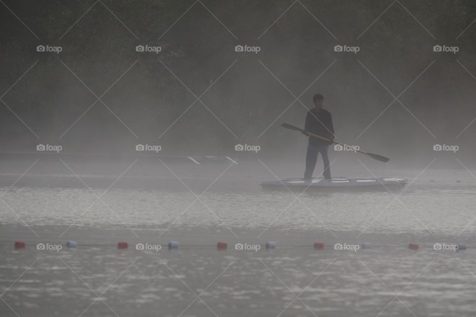 Stand Up Paddler On Misty Lake