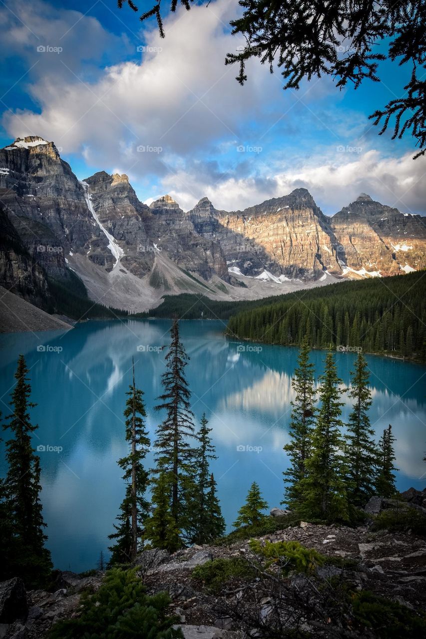 The mountains of Banff National park rise strikingly against the stark blue water of lake Moraine.