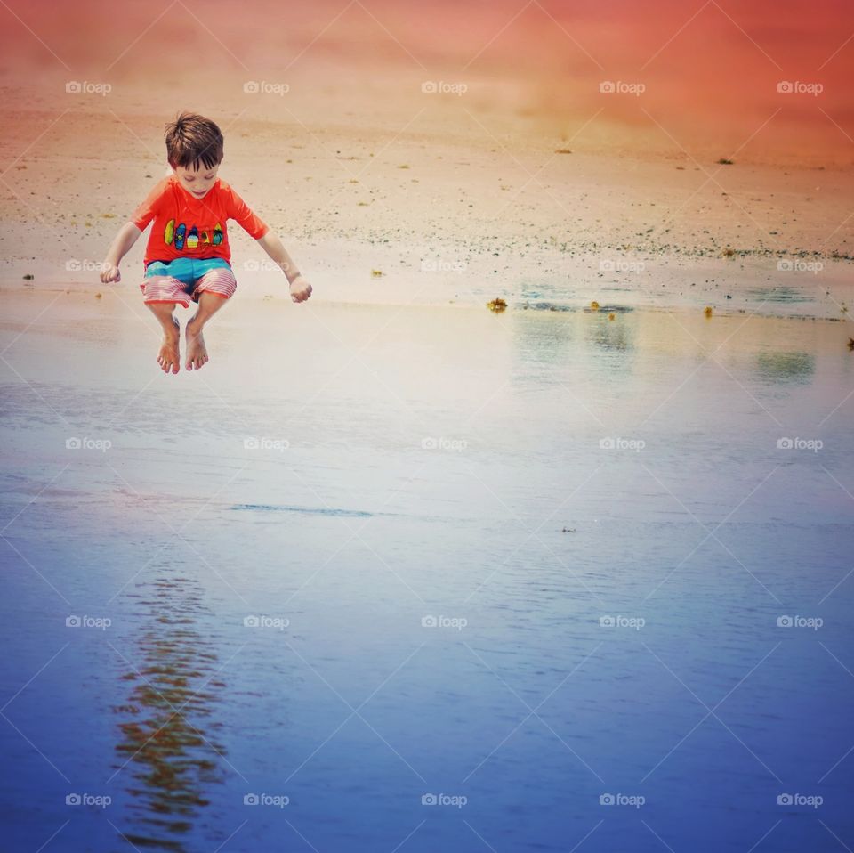 A boy jumping in mid-air at sunset on the beach