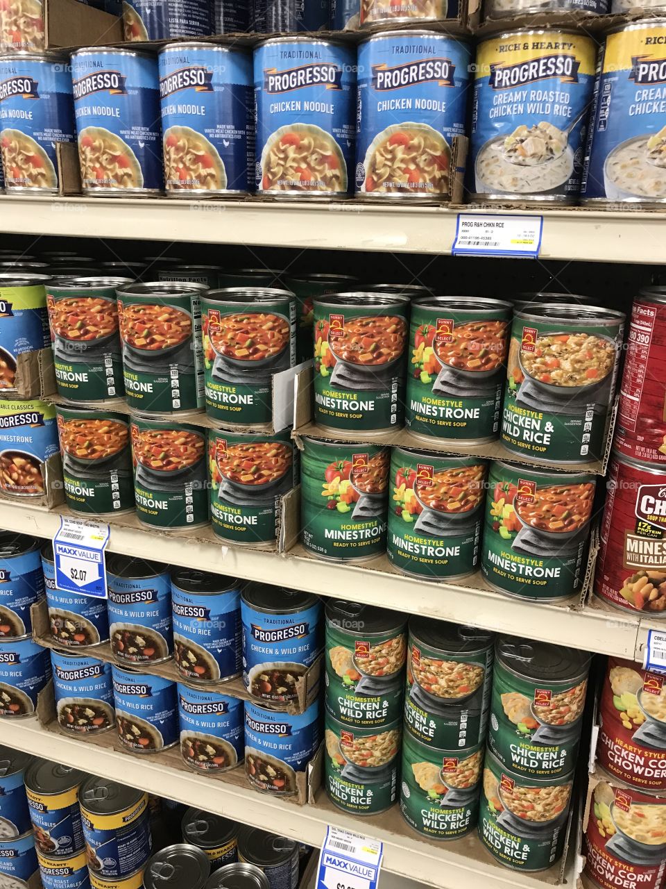 Rows of canned soups at the supermarket. There is a selection of canned edibles to choose from in terms of their types, name brands and prices.
