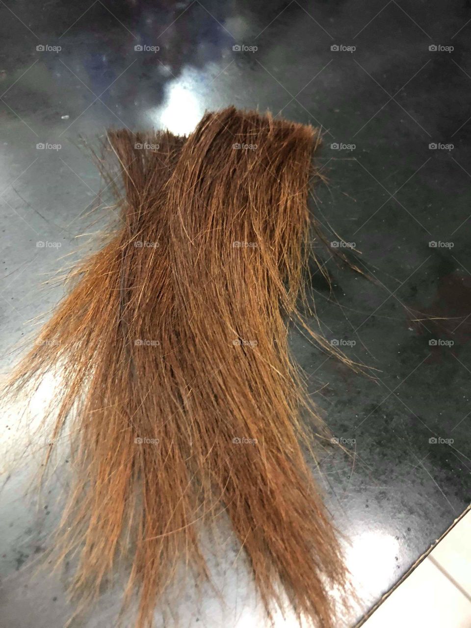 A photo of an actual cut long hair on the floor of a salon.