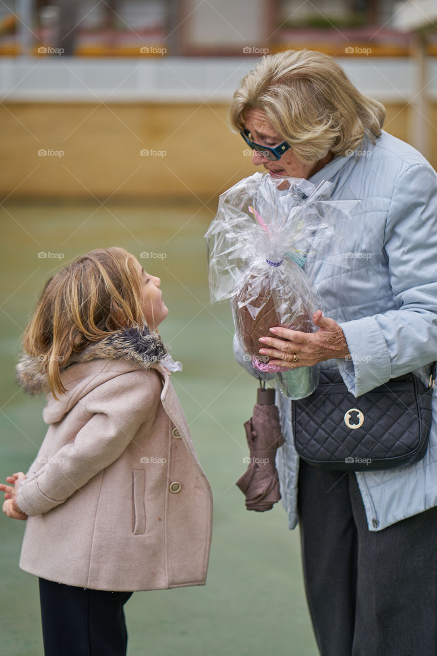 Portrait of grandmother giving gift to her granddaughter