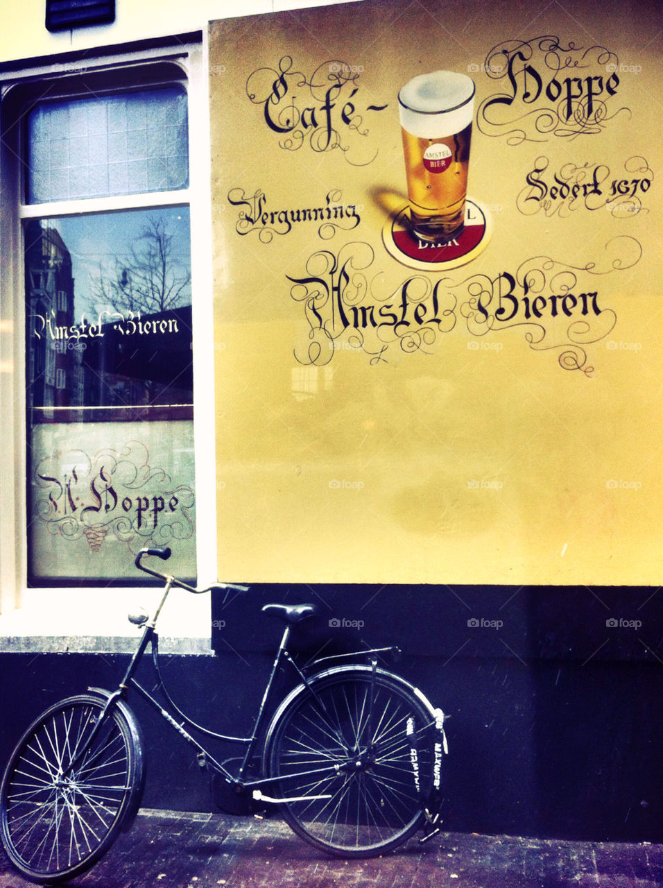A Dutch bike propped up against a yellow wall.