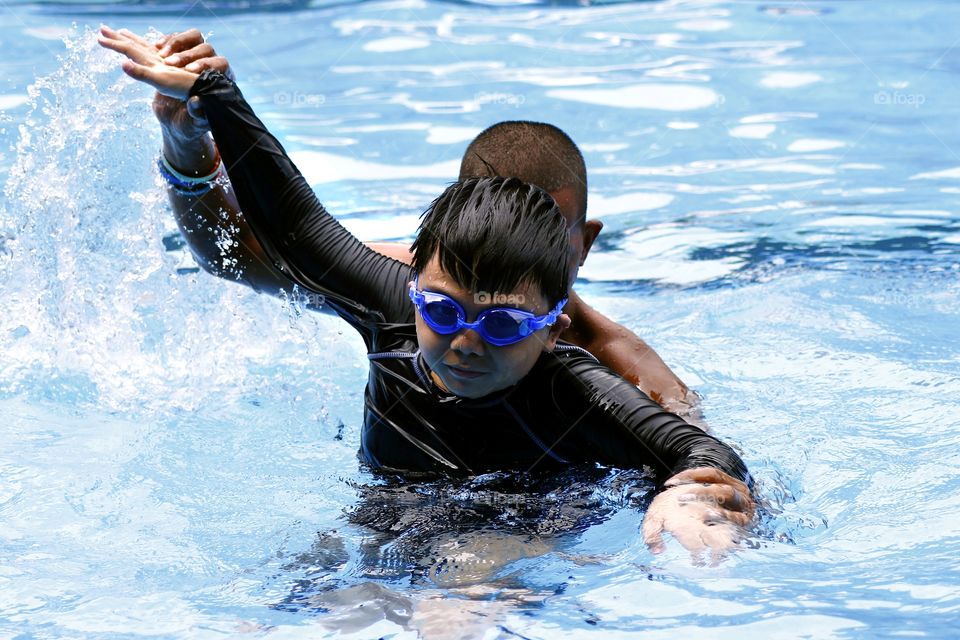 a child is taught by a swimming coach how to swim