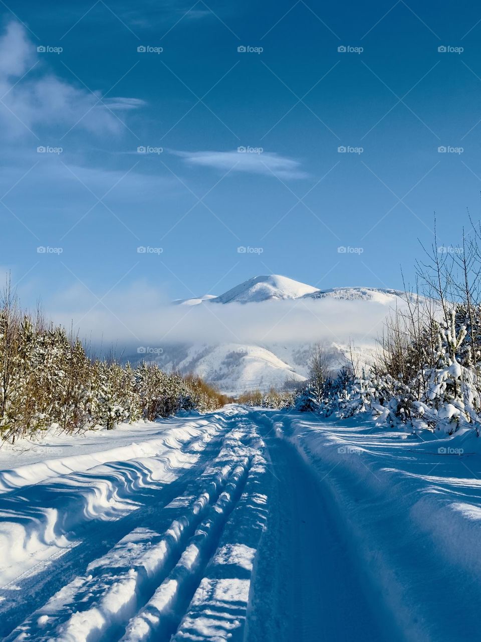 snowy road to the mountains with low clouds