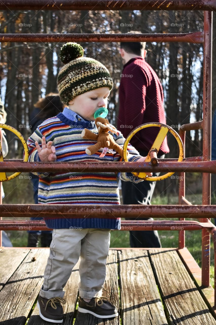 Cute toddler boy in knit sweater and hat playing outdoors