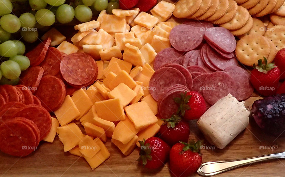 Hors d’Oeuvres plate of cheese and crackers and pepperoni and fruit strawberries grapes