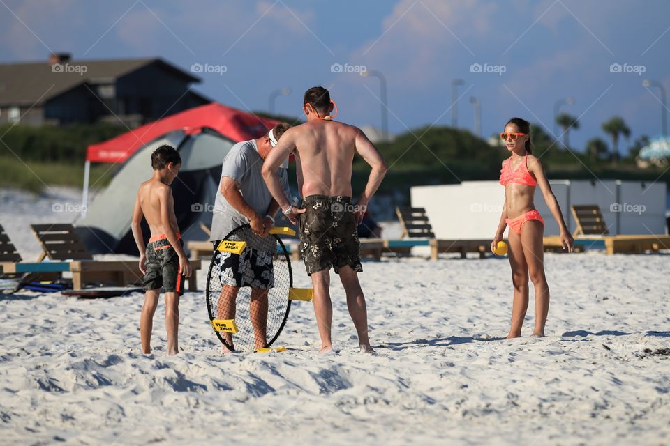 People playing ball at the beach in swimming suit 