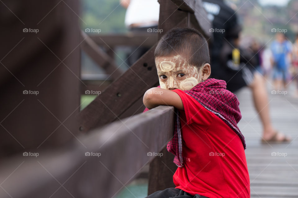 Boy sitting on the wood bridge looking at camera