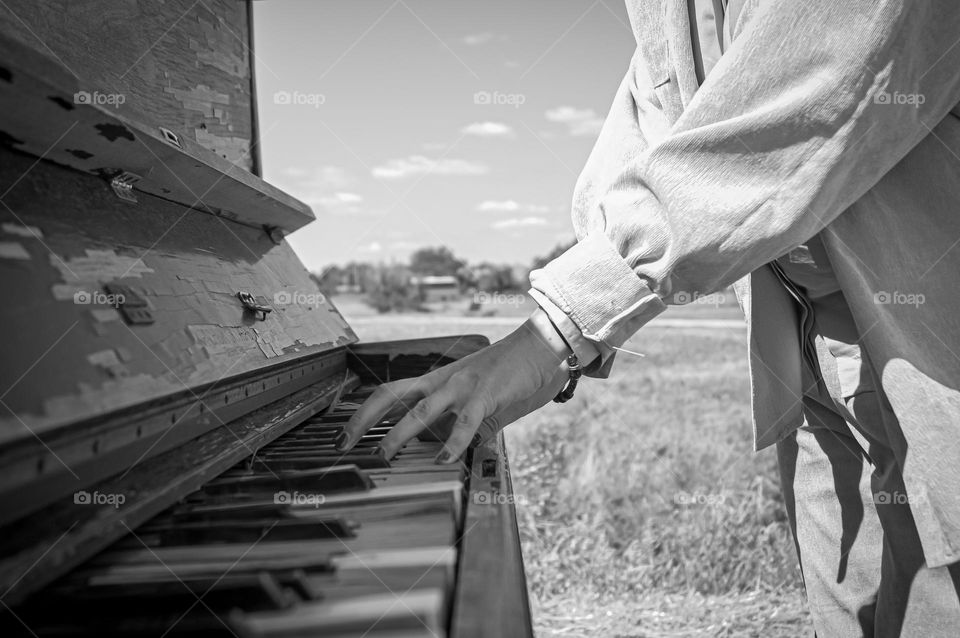 The girl plays the piano by the sea in the open air