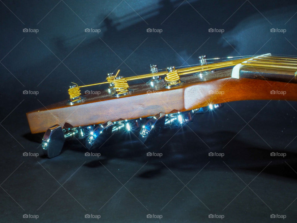 Musical instrument classical acoustic guitar of light color with steel pins and silver strings on a dark background