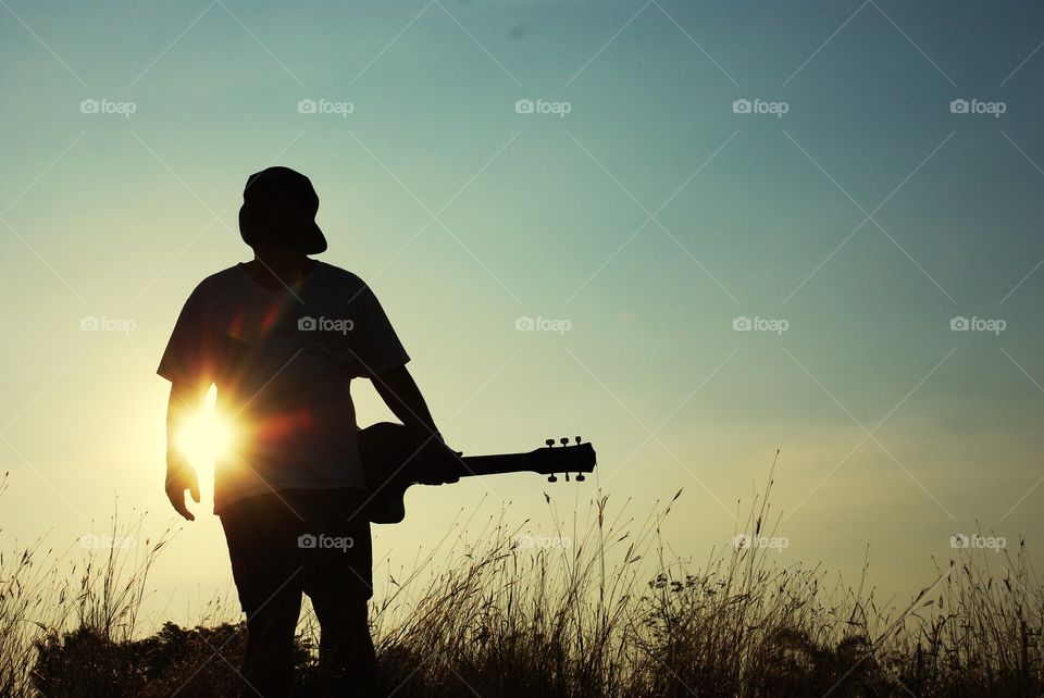 Beautiful a man holding guitar on sky background.