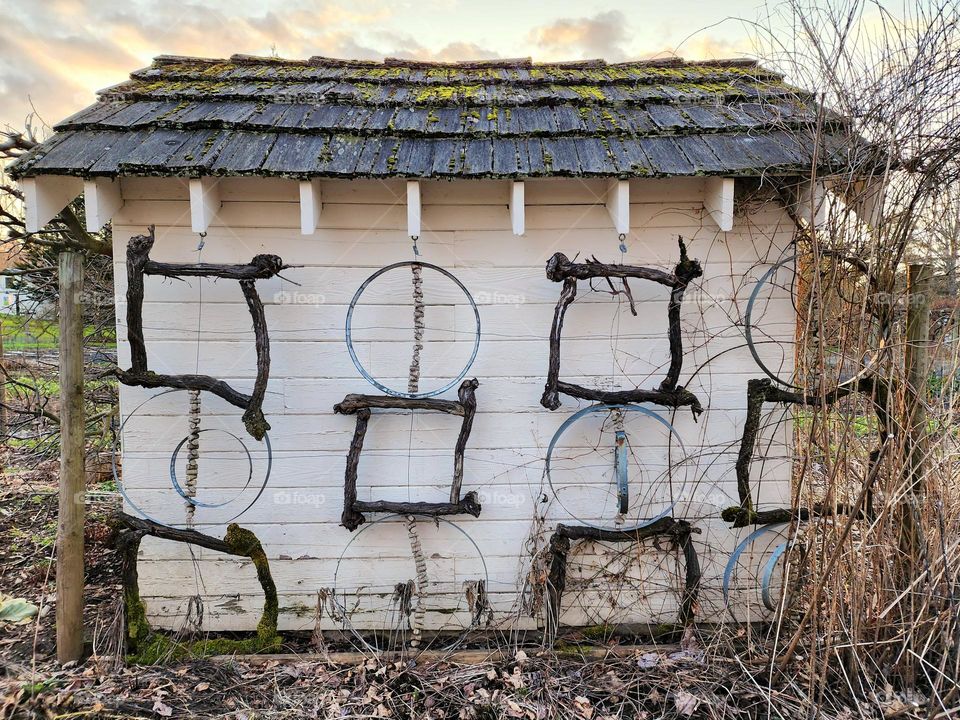 Circular metal rings hang on a wall along with some other metal forms used in various farming functions