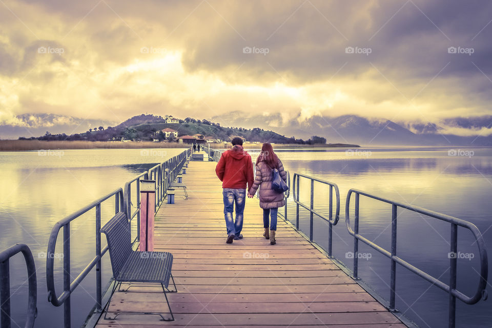 Young Couple In Love Walking Across A Bridge Holding Hands
