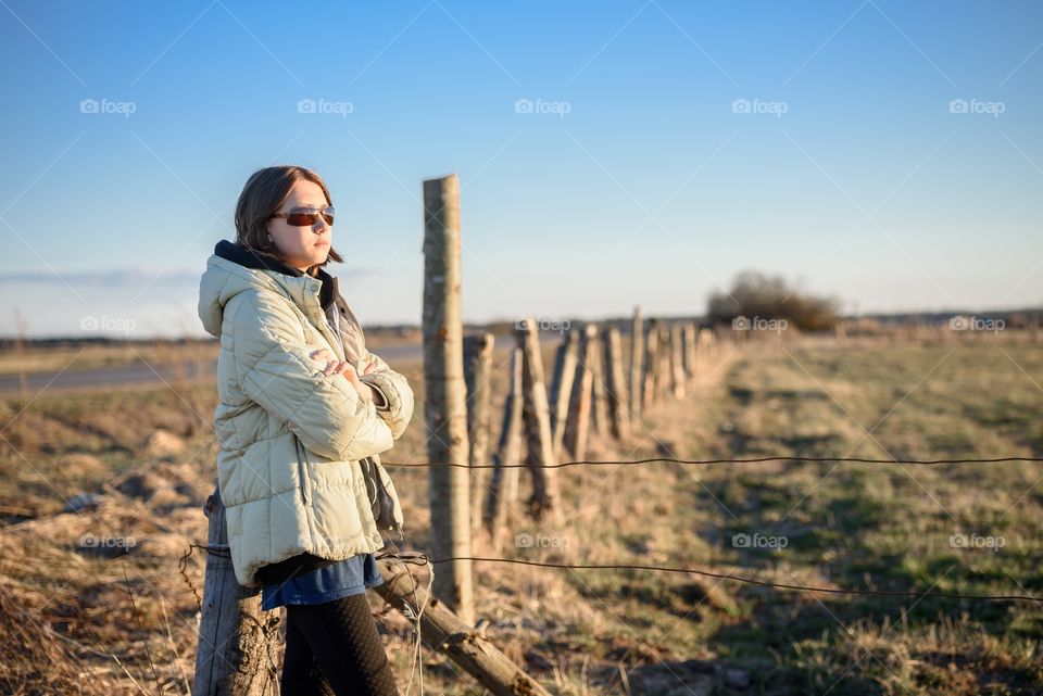 A girl in sunglasses outside the city in a village resting in the field.