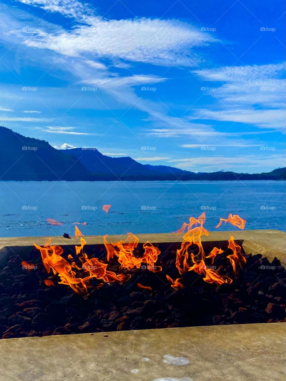 A bright orange flame against a blue sea during an Alaskan summer evening.