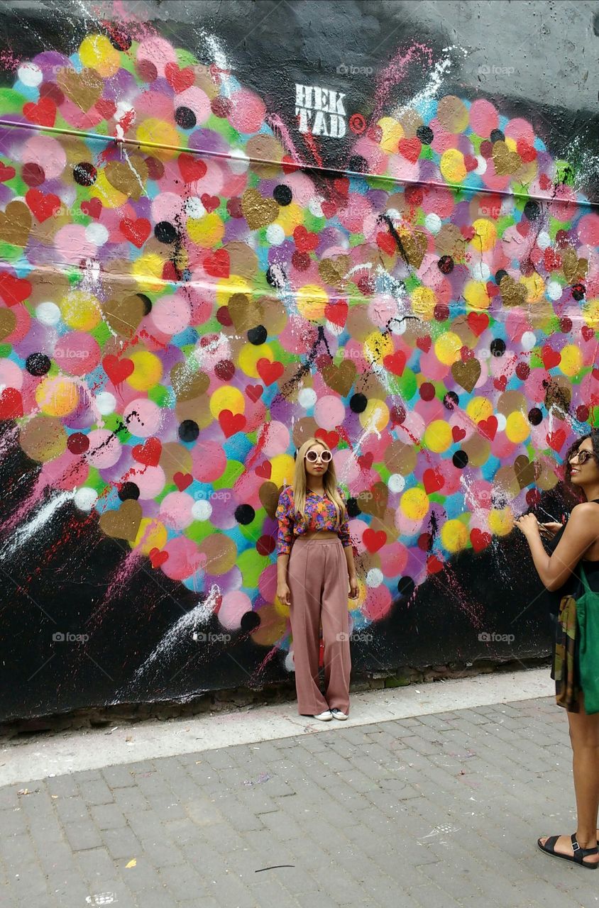 Two women taking photos in front of Graffiti