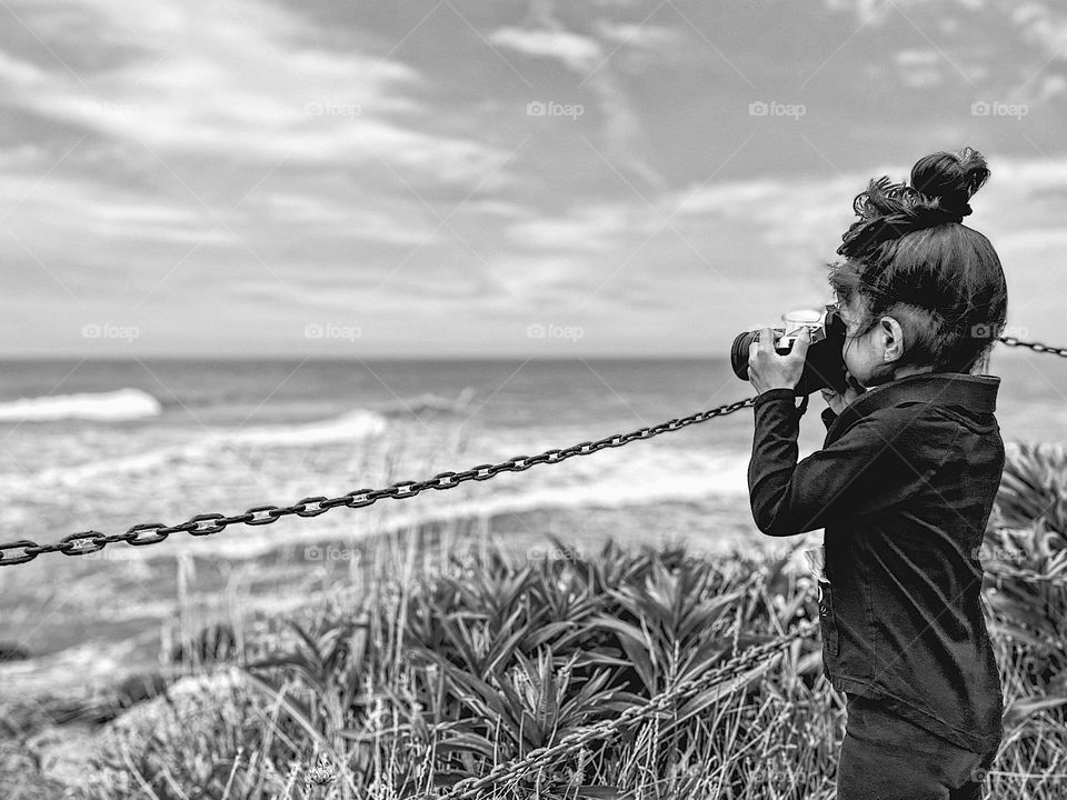 Toddler girl focuses camera, little girl takes pictures, learning the art of photography, photographer in the making, creating greatness 