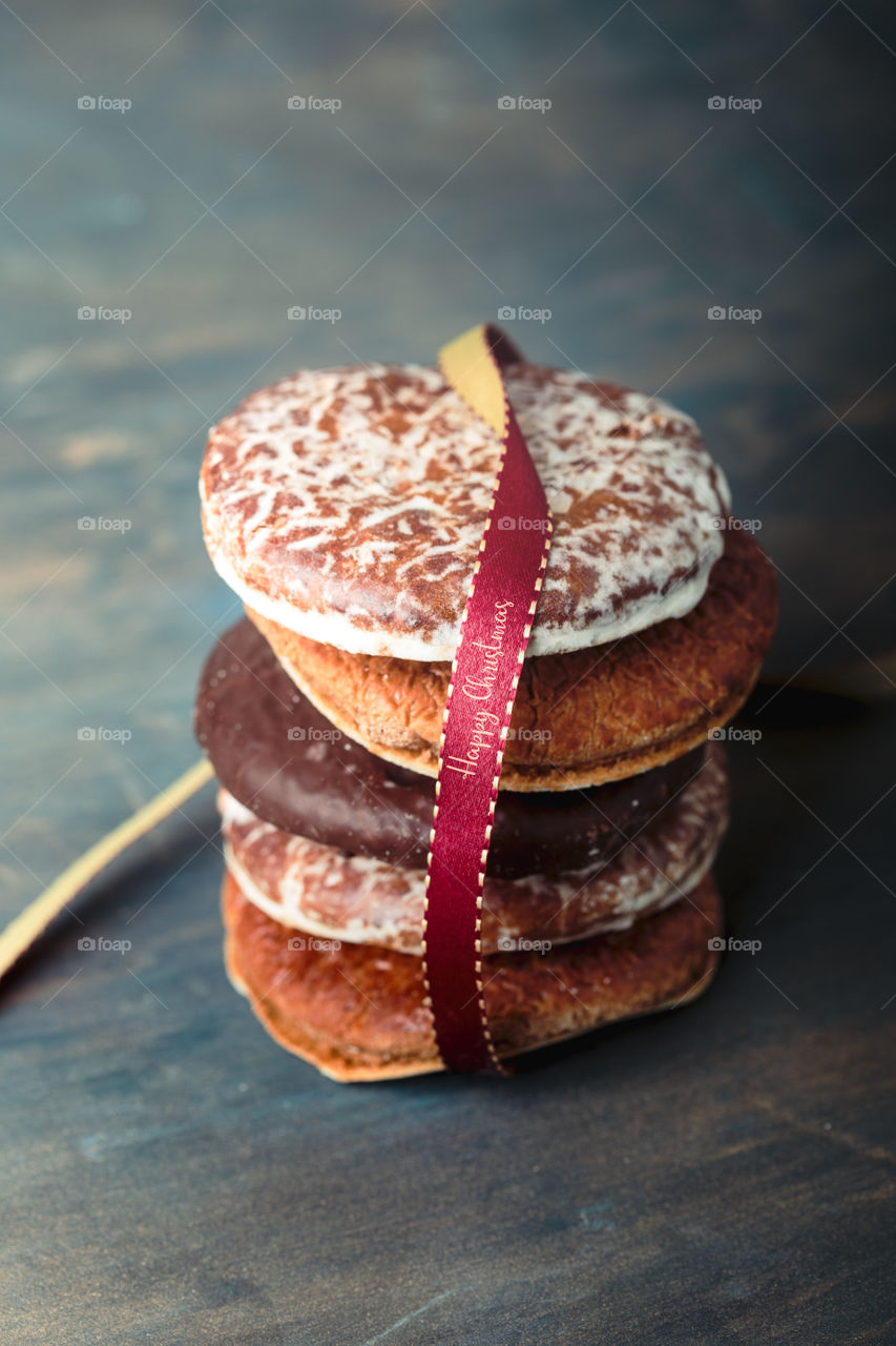 A few gingerbread cookies wrapped in red ribbon Happy Christmas on wooden table. Plain background. Portrait orientation