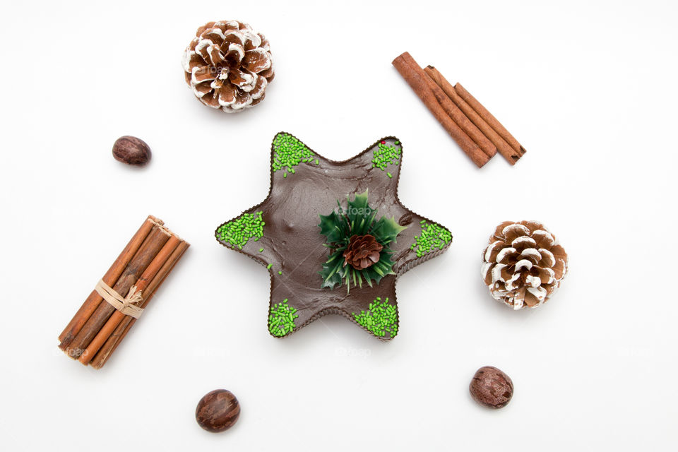 Composition Of Christmas Star Chocolate Muffin Cupcake, Pine Cone, Nuts And Cinnamon Isolated On White Background
