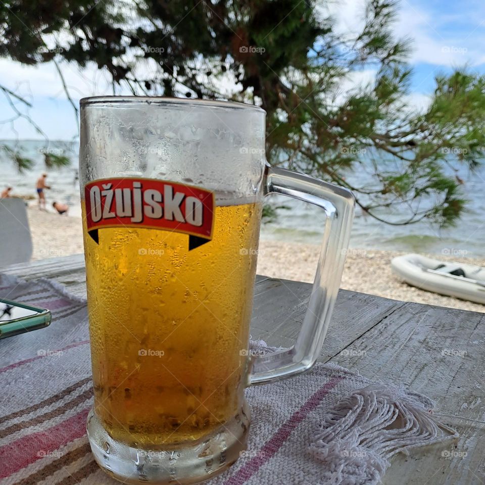 beer larger overlooking hot sunny beach in summer. croatia holiday cold drink, shady table in restaurant