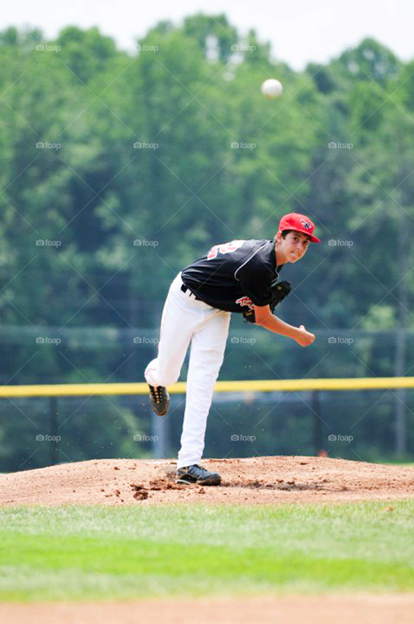 action on the  mound. young pitcher follows through on the mound