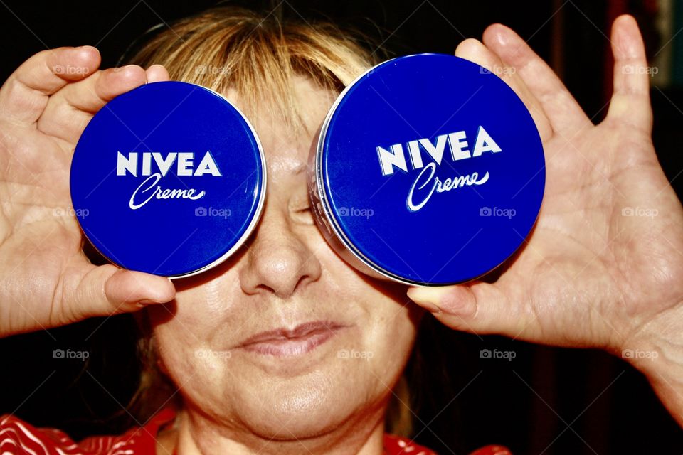 It's Nivea cream. Handcream. The model holds two boxes of Nivea cream with both hands. The two boxes of Nivea cream play the role of eyes.
