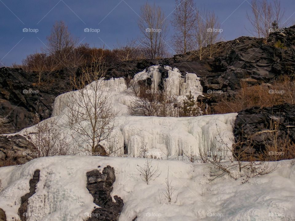 Ice waterfalls in the Pervomaisky quarry of the Zavitinsky lithium deposit. Shilkinsky district, Zabaykalsky Krai, Siberia, Russia.