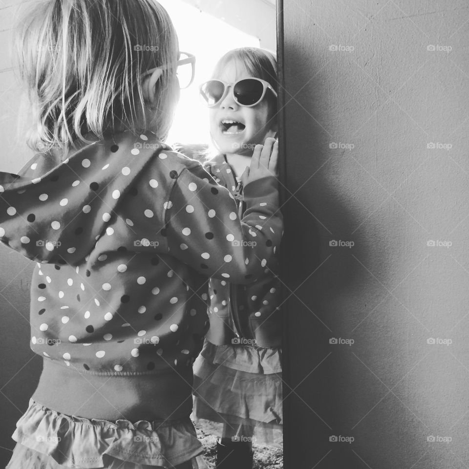 Little girl looking into the mirror. Smiling at who she is.