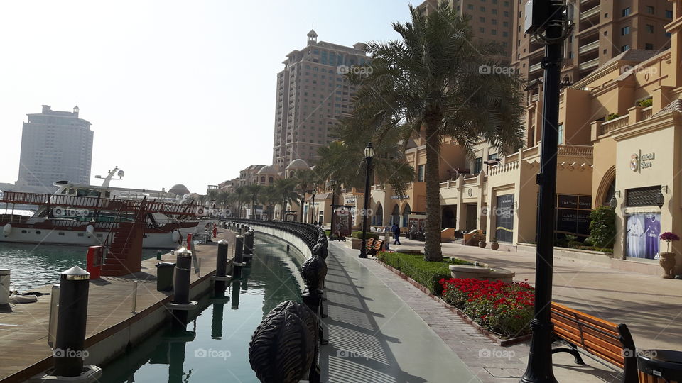 Walkway by the ocean/ Surrounded by luxury hotels/ Apartments and boats