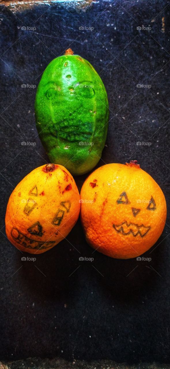 Three fruit with spooky face decoration.