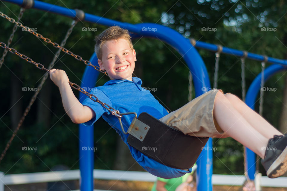 Young Boy Swinging on a Blue Swing-set at Playground