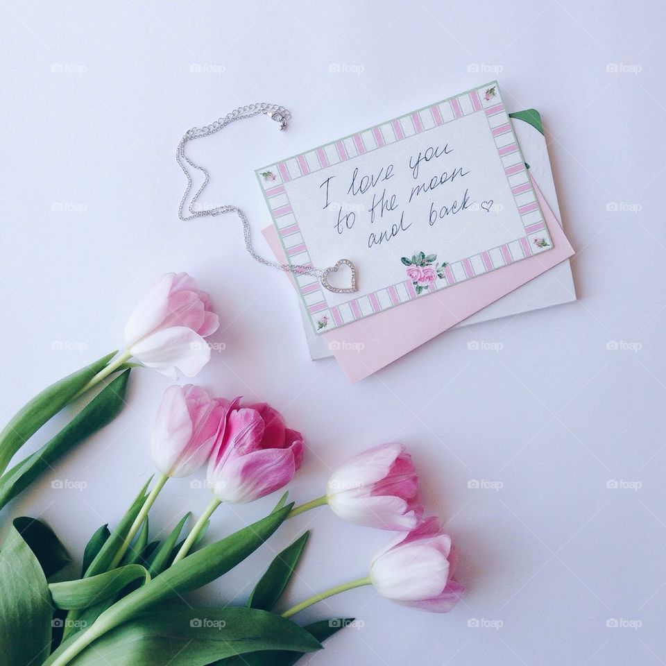 Greeting card with silver chain and tulips flower on pink background