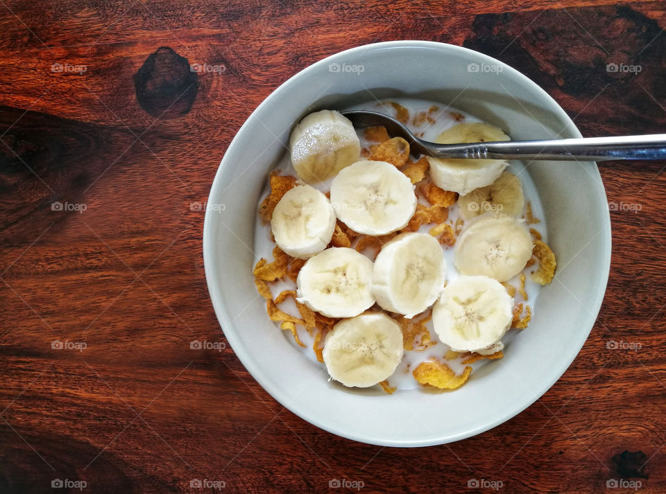 Cornflakes and banana with milk for breakfast.  Healthy food.  Cereal and banana with milk.