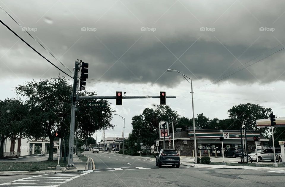 Road trip slower drive in the city or town by the traffic lights seeing other cars driving in the same side and opposite side with gas station.