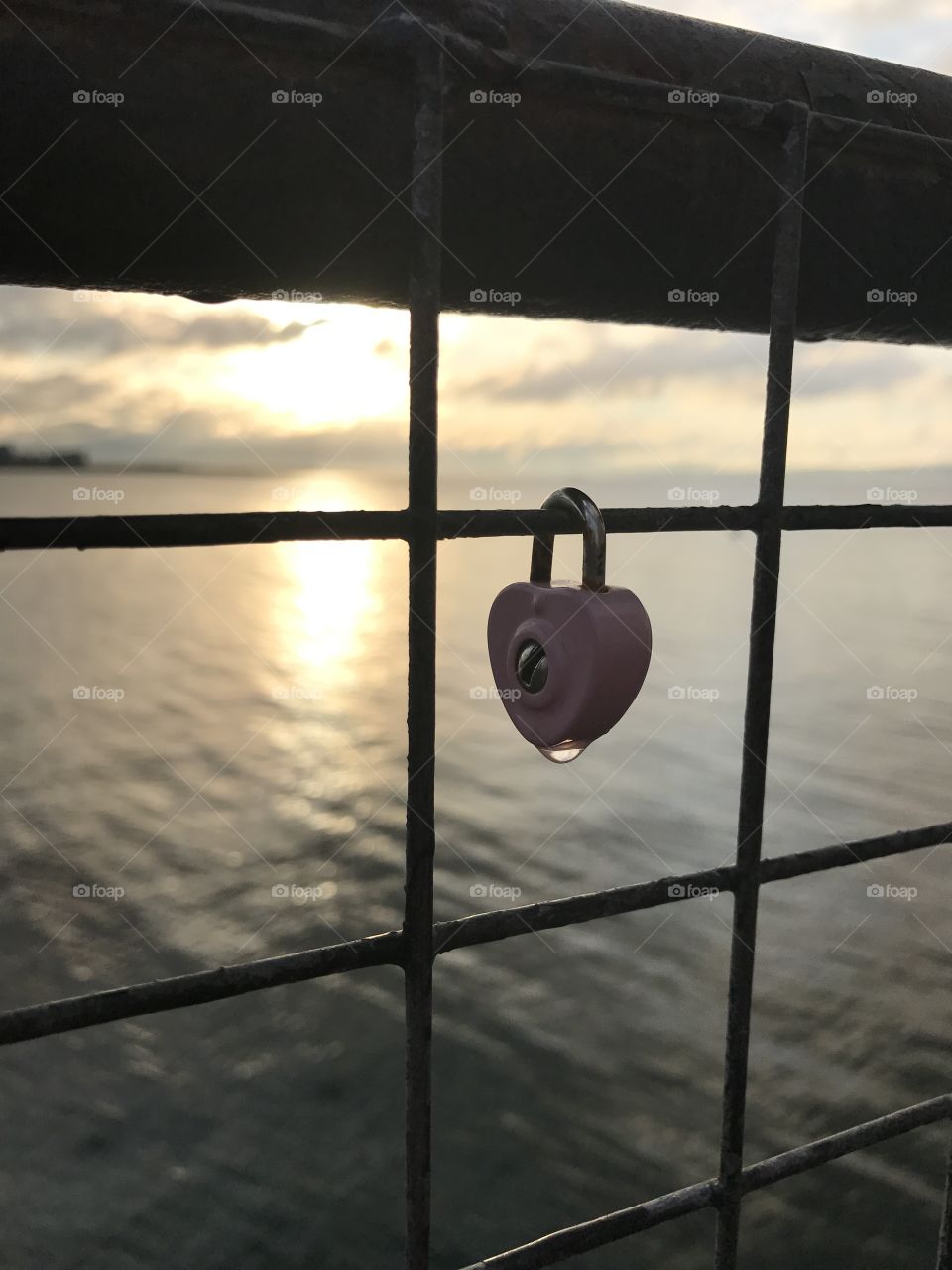A water drop  glistens on a heart-shaped lock silhouetted by the setting sun at Newhaven Harbour in Scotland