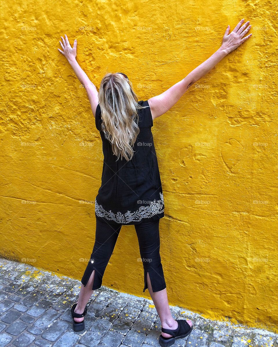 Girl posing by yellow wall