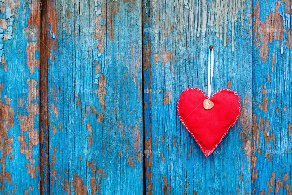 Red heart hanging on blue wooden door