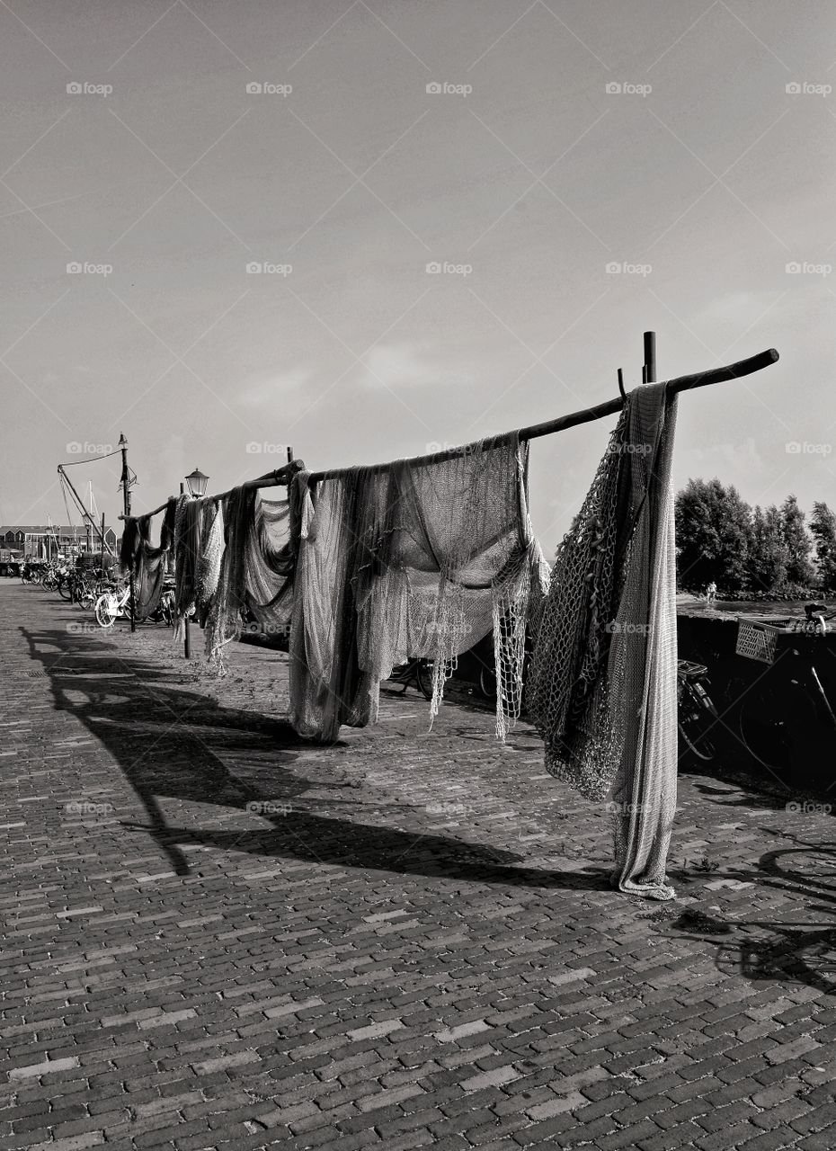 shadows of fishing nets hanging on the edge of the harbor of the city of Urk, Netherlands