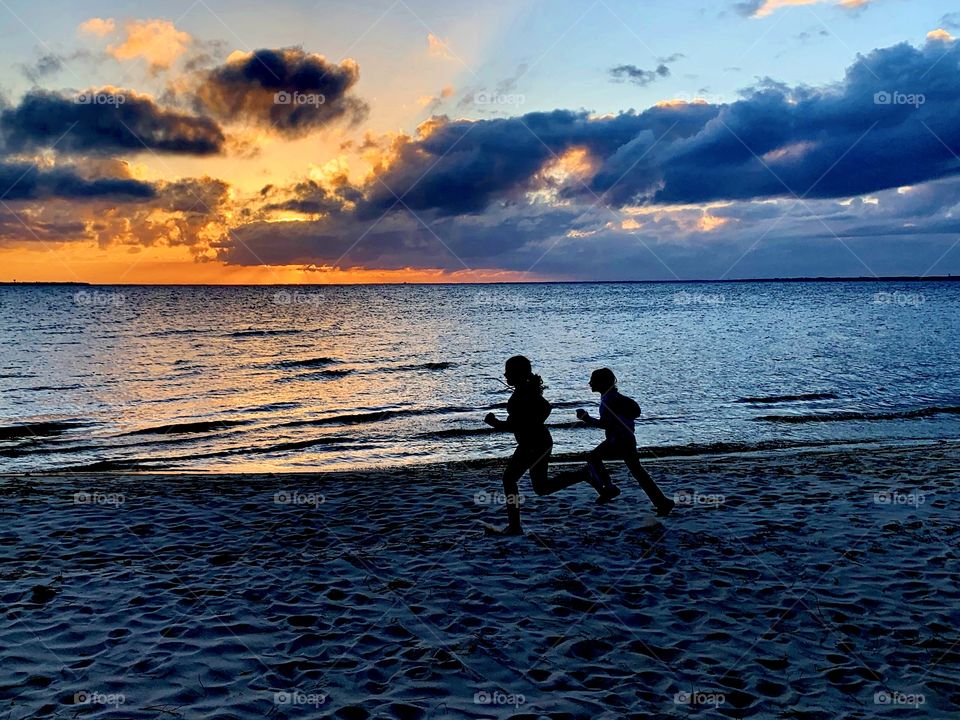 

Kids running on the beach as the  big orange and crimson ball slowly going down and down and it sets into the horizon making the sky absolutely stunning. 
